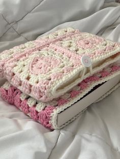 two crocheted blankets sitting on top of a bed next to an electronic device