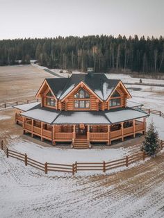 an aerial view of a large wooden house in the middle of a snow covered field