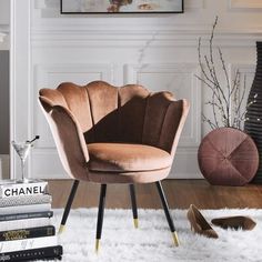 a chair sitting on top of a white rug next to a pile of books in a living room