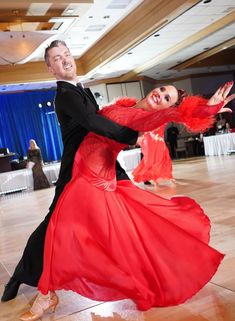 a man and woman in red dress dancing on the dance floor at a wedding reception