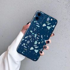 a woman holding up an iphone case with blue and white speckles on it