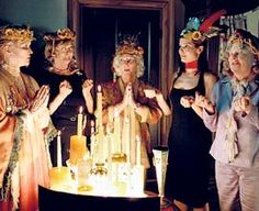 five women standing around a birthday cake with candles on it and one woman holding her hands up