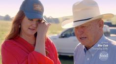 an older man wearing a hat talking to a woman