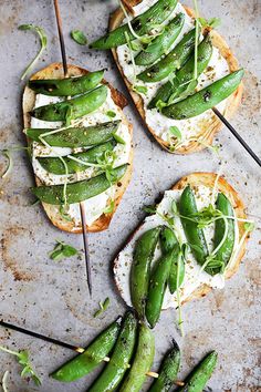 three pieces of bread topped with green beans and cream cheese on skewers next to asparagus