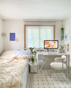 a bed room with a neatly made bed and a computer on top of the desk