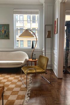 a living room filled with furniture and a lamp on top of a hard wood floor