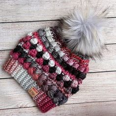 a crocheted hat with a white pom - pom sitting on top of it