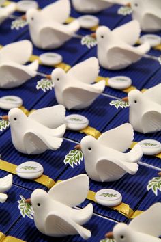 several white birds are on a blue table cloth with gold ribbons and bows around them