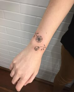 a woman's hand with a flower tattoo on her left wrist and the other arm