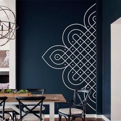 a dining room with a table and chairs in front of a wall painted with an intricate design