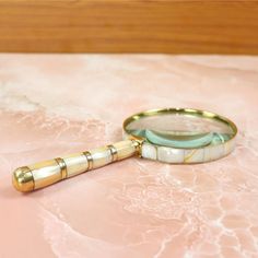 a magnifying glass sitting on top of a pink table next to a wooden object