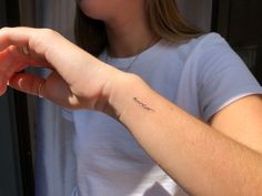 a woman with a small tattoo on her left arm and the word love written in cursive writing