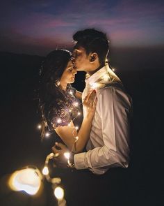 a man and woman standing next to each other in front of the sky with lights