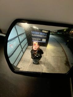 a person sitting on the sidewalk in front of a mirror