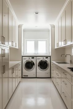 a washer and dryer are in the middle of a long white kitchen with cabinets