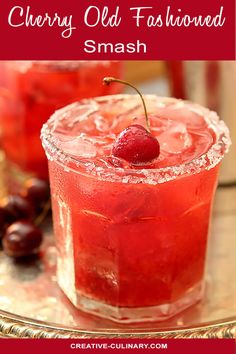 two glasses filled with ice and cherries on top of a metal tray next to some fruit