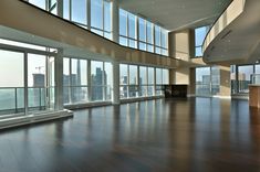 an empty room with wooden floors and large windows overlooking the cityscape in the distance