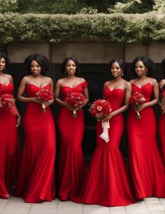 a group of women in red dresses standing next to each other and holding bouquets