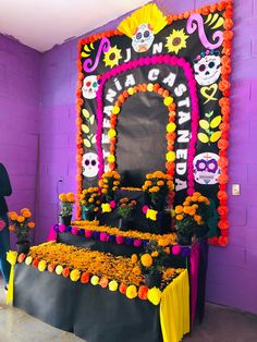 an altar decorated with flowers and skulls in front of a purple wall that says dia de los muerts