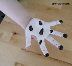 a child's hand painted with black spots on white paper and wood planks