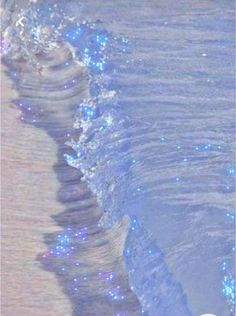 an ocean wave is coming towards the shore with blue lights on it's side