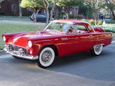 an old red car is parked on the street