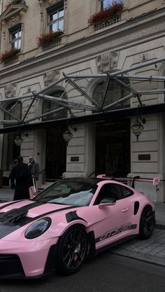 two pink sports cars parked in front of a building