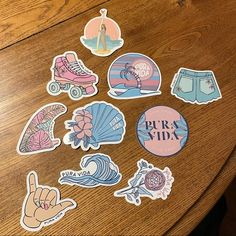 various stickers on a wooden table with a person standing in the distance and holding up their hand