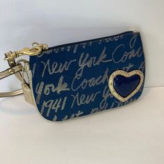 Blue Signature Coach Small Wristlet With Blue Heart, Gold Accents And Gold Wrist Strap. Item Is New Without Tags Trendy Coach Clutch As Gift, Trendy Blue Clutch For Gift, Blue Travel Wristlet With Removable Pouch, Blue Rectangular Bag With Wrist Strap, Blue Wristlet With Removable Pouch For Travel, Blue Bags With Wrist Strap For Daily Use, Trendy Coach Wristlet As Gift, Trendy Coach Clutch Wristlet, Blue Wristlet With Zipper Pouch For Travel