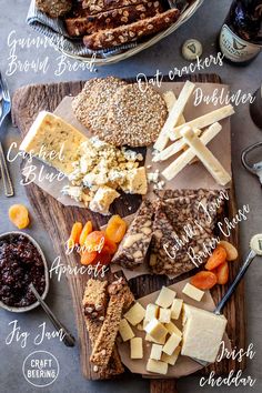 an assortment of cheeses and crackers on a cutting board with other foods around it