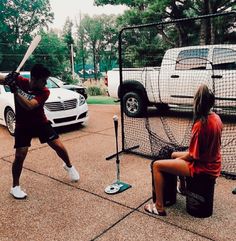 two people are playing baseball in the parking lot