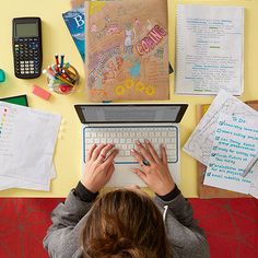 a woman is typing on her laptop in front of the desk full of school supplies