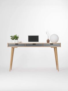 an office desk with two drawers and a laptop on it, in front of a white wall