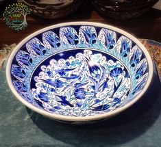 a blue and white bowl sitting on top of a table next to other bowls in the background