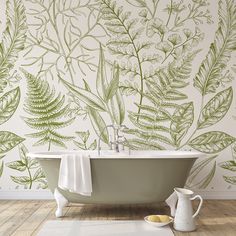 a bath tub sitting next to a wall with green leaves on it