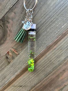 a keychain hanging from a glass tube filled with water and green algaes