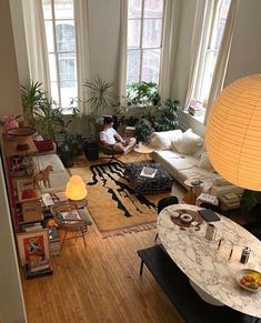 a living room filled with lots of furniture next to two large windows and a lamp