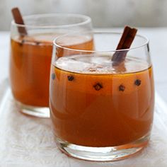 two glasses filled with liquid and cinnamon sticks