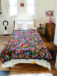 a bed with colorful bedspread and pillows on top of it in a bedroom