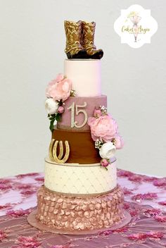 a three tiered cake with pink flowers and gold boots on top, sitting on a table