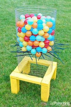 a bunch of balls that are in a cage on the grass near a table and chair