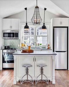 an open kitchen with white cabinets and wooden floors