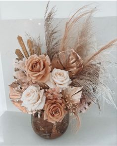 a vase filled with flowers and feathers on top of a table