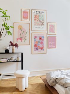 a bedroom with white walls and pictures on the wall