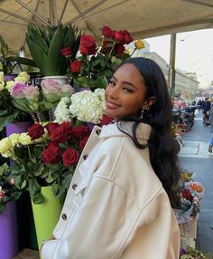 a woman standing in front of flowers under an umbrella