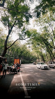 some cars and motorcycles are parked on the side of the road with trees in the background