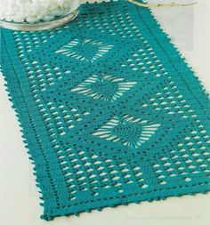 a blue crocheted table runner next to a bowl of cotton