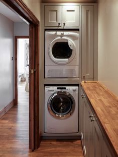 a washer and dryer in a small room with wood flooring on the side