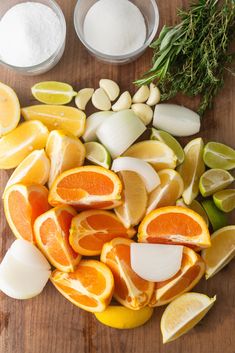 oranges, lemons and garlic are cut up on a cutting board with spices