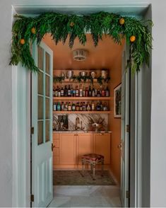 an open door leading to a kitchen with plants growing on the wall and shelves above it